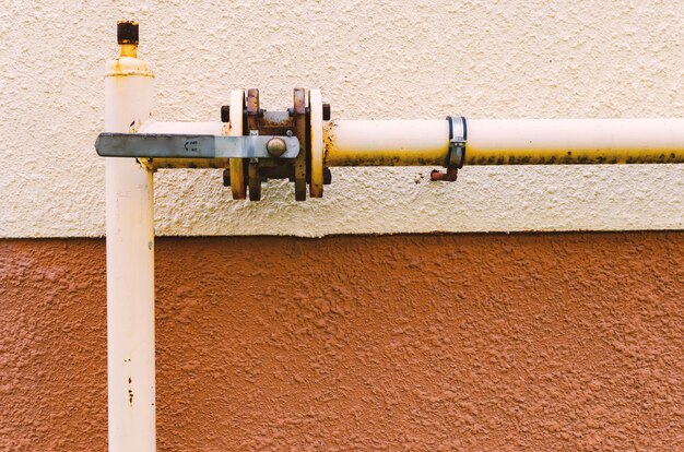 Un tuyau de gaz jaune avec une grue longe la façade d'un nouveau bâtiment à plusieurs étages.