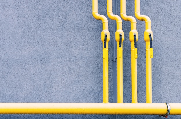 Un tuyau de gaz jaune avec une grue longe la façade d'un nouveau bâtiment à plusieurs étages.