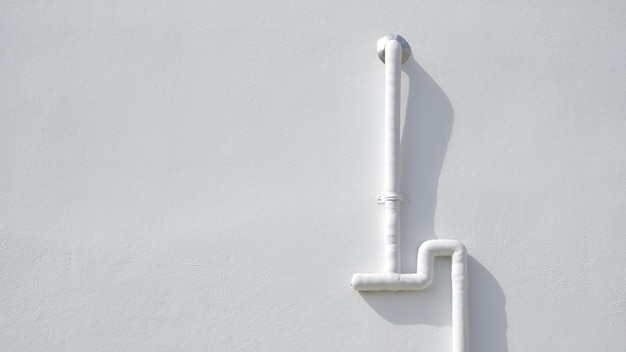 Tuyau de protection en PVC blanc avec câbles électriques à l'intérieur sur un mur de ciment blanc à l'extérieur du bâtiment