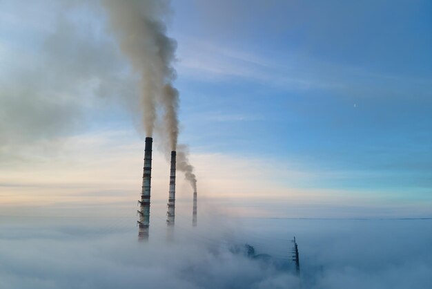 Tuyaux hauts de la centrale électrique au charbon avec de la fumée noire se déplaçant vers le haut de l'atmosphère polluante. Production d'énergie électrique avec le concept de combustible fossile