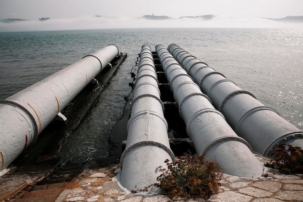 Tuyaux industriels sur la mer contre le ciel