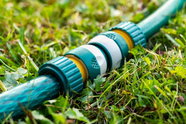 Photo tuyaux d'irrigation de jardin connectés à un connecteur de tuyau en plastique moderne allongé sur l'herbe