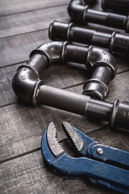 Tuyaux et raccords en fonte de différentes formes et formes posés sur une table en bois rustique