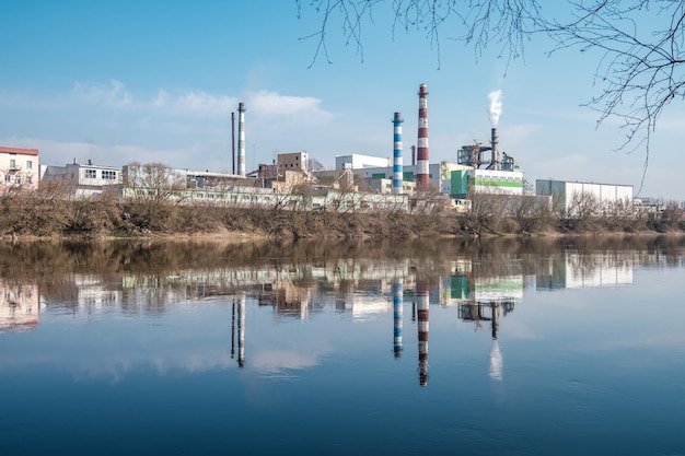 Tuyaux de la scierie de l'usine de menuiserie près de la rivière Concept de pollution de l'air Paysage industriel pollution de l'environnement déchets de la centrale thermique