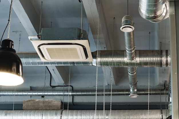 Des tuyaux de ventilation en argent suspendus au plafond à l'intérieur du bâtiment