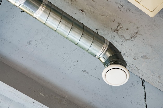 Des tuyaux de ventilation en argent suspendus au plafond à l'intérieur du bâtiment