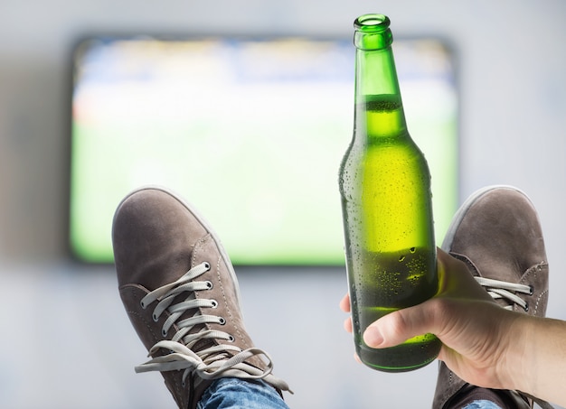 TV sur le mur Et une bouteille de bière