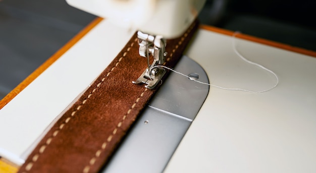 Type d'arrière-plan de la machine à coudre, processus de couture de la ceinture en cuir. Atelier de cuir.