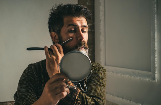 Un type brutal dans un barbier moderne passe un bon moment au barbier en faisant une coupe de cheveux attrayante