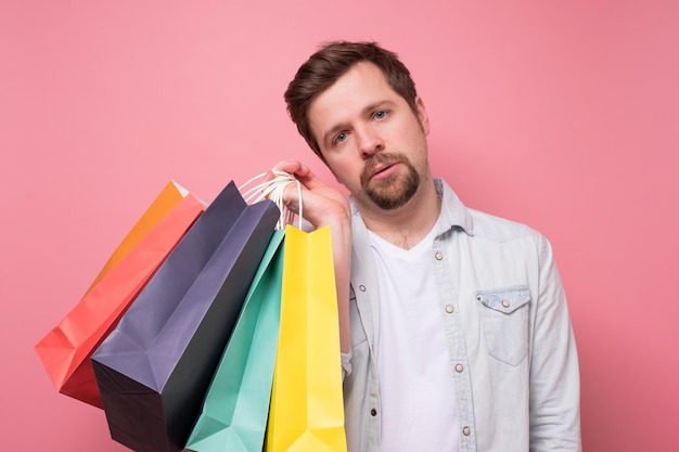 Type caucasien fatigué tenant des sacs à provisions