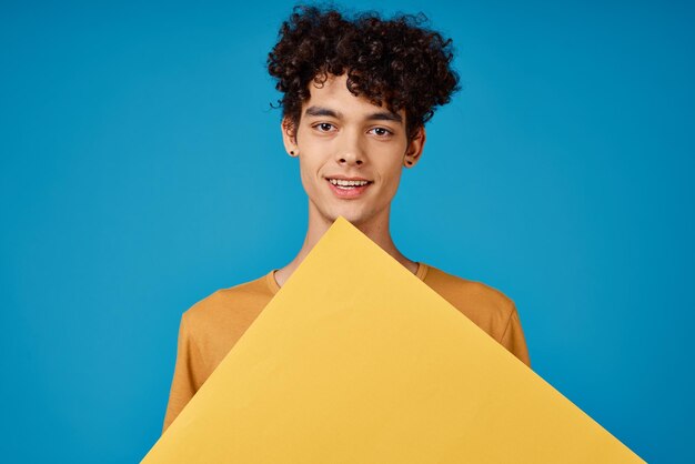 Photo un type joyeux avec des cheveux bouclés d'astères jaunes dans ses mains fond bleu studio photo de haute qualité