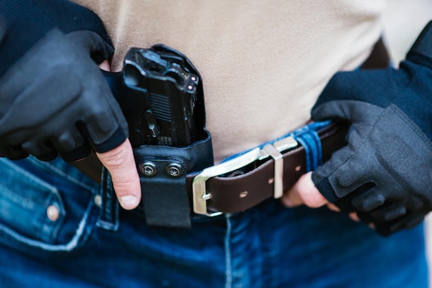 Le type met l'arme dans l'étui en gros plan.