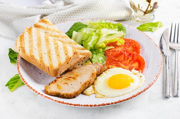 Œuf au plat avec des tranches de tomates de porc et des toasts Délicieux petit-déjeuner anglais Brunch