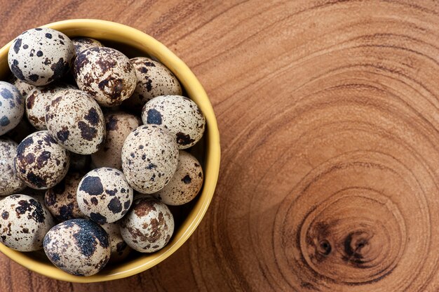 Œuf de caille dans un bol et table en bois