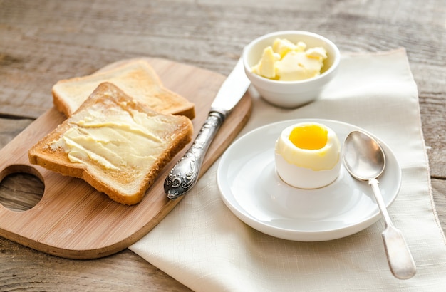 Œuf à la coque avec des toasts croustillants et du beurre sur la table en bois