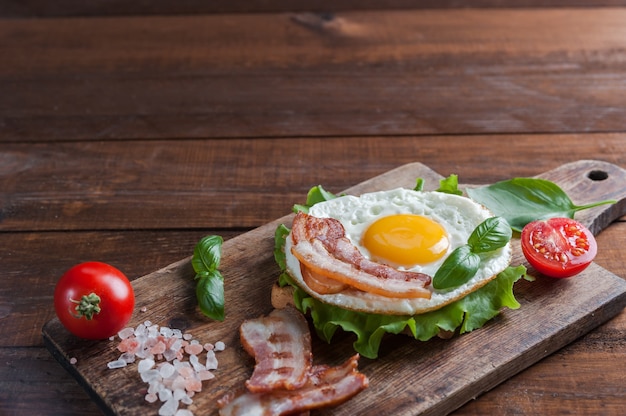 Œuf frit et bacon sur planche à découper, table rustique en bois, mise au point sélective