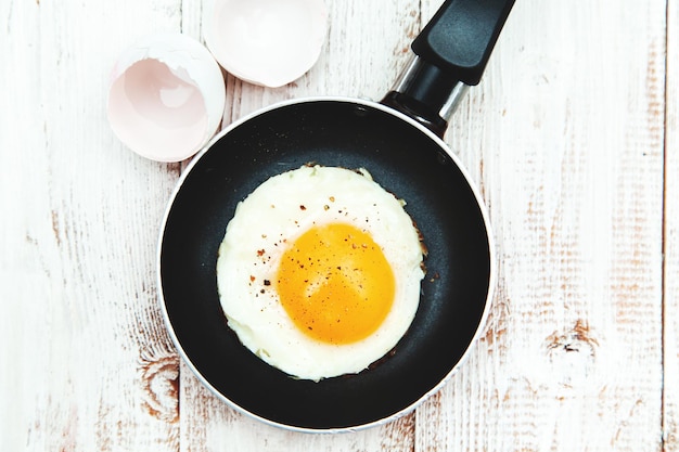 Œuf frit dans une poêle à frire sur un fond de bois petit-déjeuner anglais traditionnel fond alimentaire