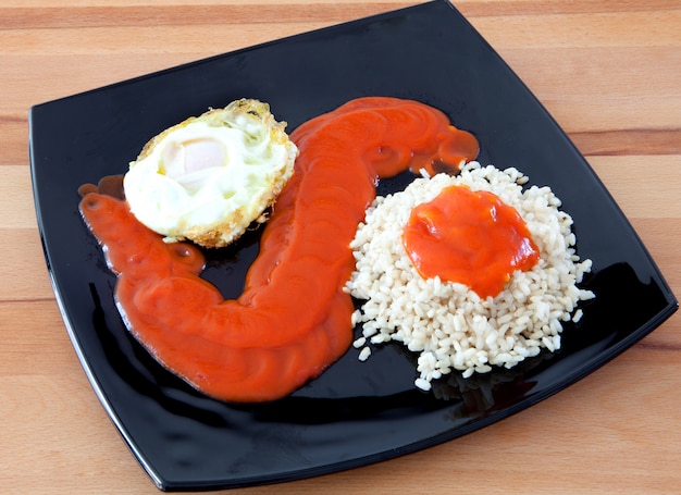 Œuf frit avec du riz trop cuit et de la tomate