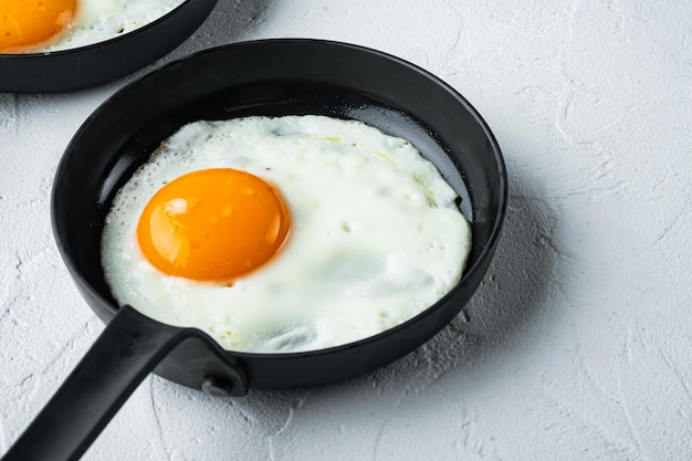 Œuf frit avec des ingrédients dans une poêle en fonte sur fond blanc