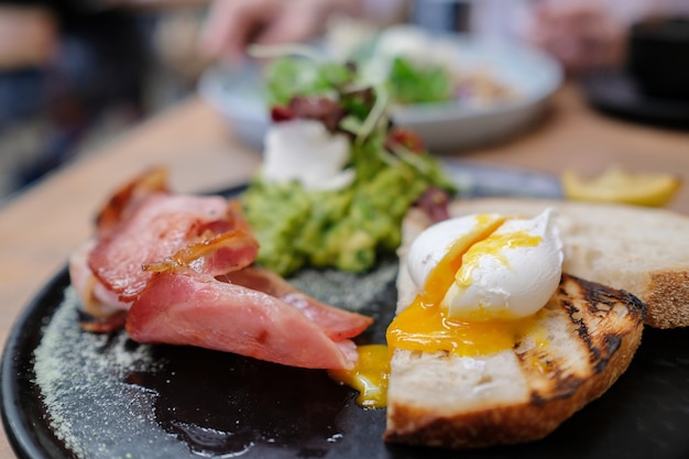 Œuf poché sur du pain au levain avec du bacon et de la purée d&#39;avocat