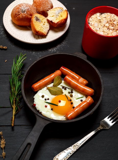 Œuf de poulet frit avec des saucisses dans une poêle à frire