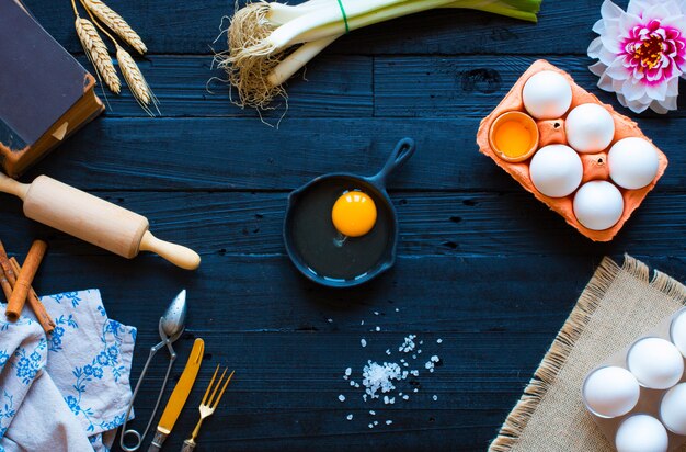 Œuf de poulet avec des ustensiles de cuisine sur une table en bois