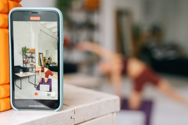 UFA, RUSSIE - 15 MAI 2020. Vue sur l'écran du téléphone d'une jeune femme en forme avec un corps athlétique parfait portant des vêtements de sport regardant un flux en ligne sur un ordinateur portable et faisant de l'exercice sur le sol. Concept de mode de vie sain