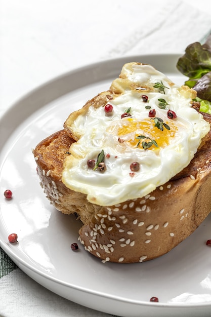 Œufs au plat maison avec brioche et salade de laitue sur plaque blanche