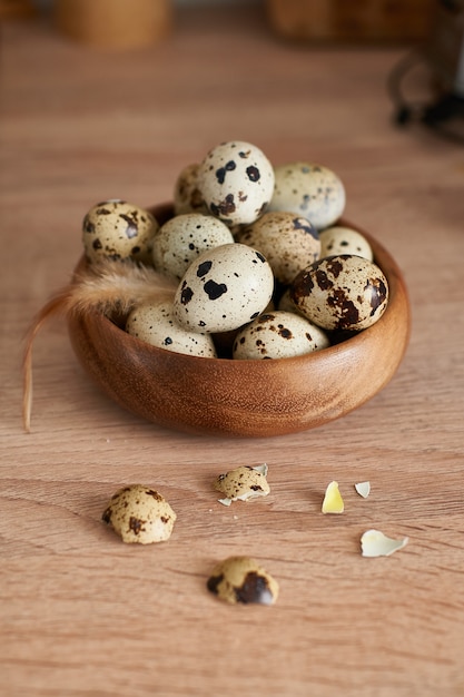 Œufs de caille dans un bol en bois peint avec une plume sur une table en bois. Espace de copie de concept de Pâques