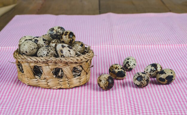 Œufs de caille dans un panier de bambou Sur le vieux fond de table en bois.