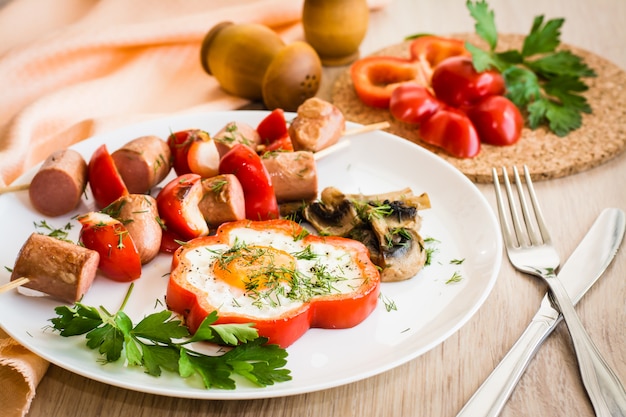 Œufs dans les poivrons, les champignons et les saucisses avec les poivrons sur des brochettes