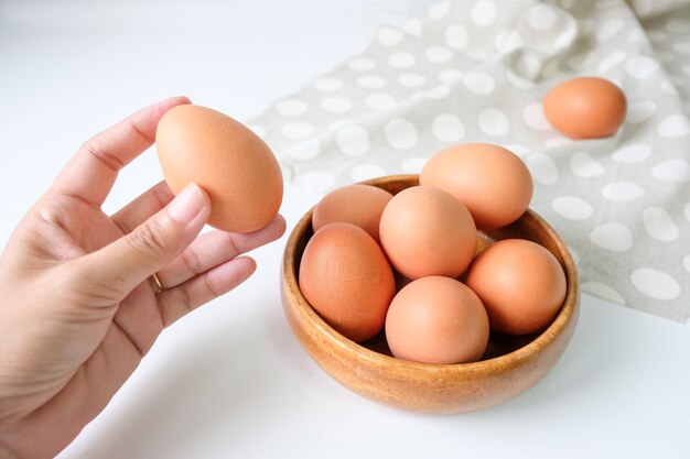 Œufs frais de la ferme placés sur un fond de table en bois blanc