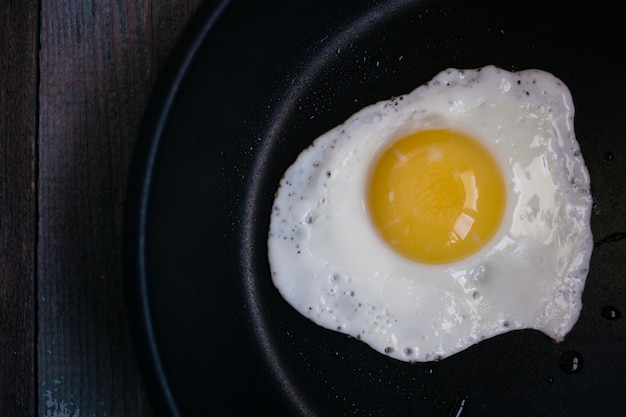 Œufs sur le plat dans une poêle sur une table en bois, petit déjeuner, vue de dessus