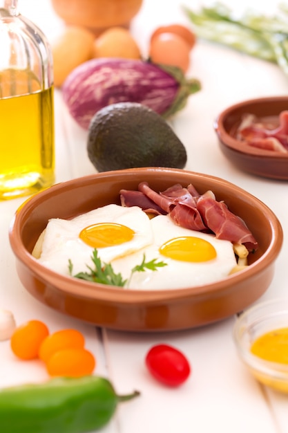 Œufs sur le plat dans une tasse en céramique avec du jamon espagnol