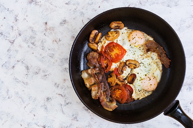 Œufs sur le plat avec du bacon, des tomates et des champignons