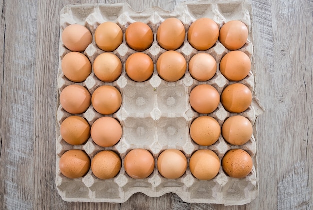 Œufs de poule dans une boîte en carton sur une table en bois.