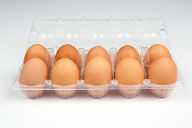 Œufs de poule dans une boîte sur fond blanc