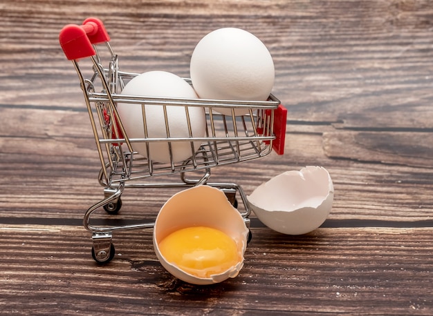 Œufs de poule dans un mini panier d'épicerie sur une table en bois brun. Fermer.