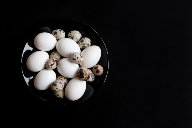 Œufs de poulet et de caille sur une plaque noire