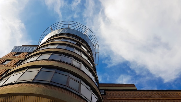 Ukraine, Kiev - 20 août 2019 : Un grand bâtiment brun avec des fenêtres au soleil et à l'ombre sous un ciel bleu et des nuages blancs. Photo prise de bas en haut.