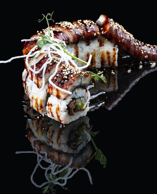 Photo unagi dragon roll avec anguille sur fond noir brillant