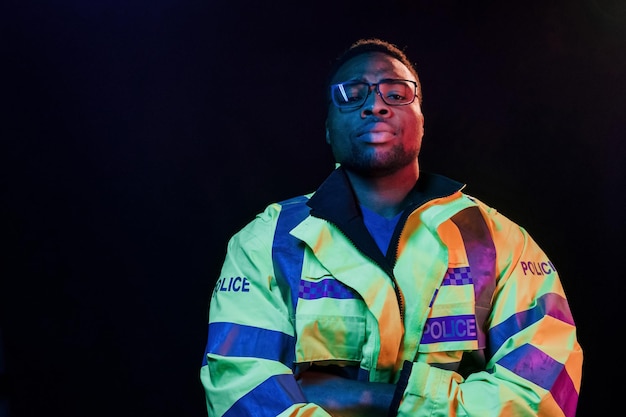 En uniforme de police Éclairage néon futuriste Jeune homme afro-américain dans le studio
