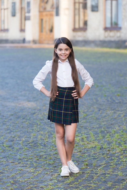 Uniforme de style formel de petite fille dans la cour d'école, concept de journée de la connaissance.