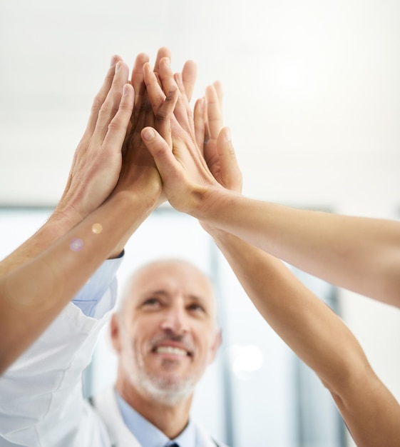 Unis dans la lutte contre la maladie Photo recadrée d'un groupe de médecins se donnant un high five dans un hôpital