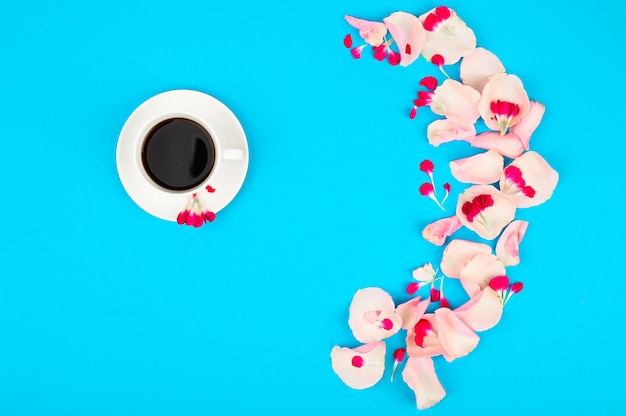 Ã Â¡up de café et de pétales de rose sur une table bleue. Bonjour concept