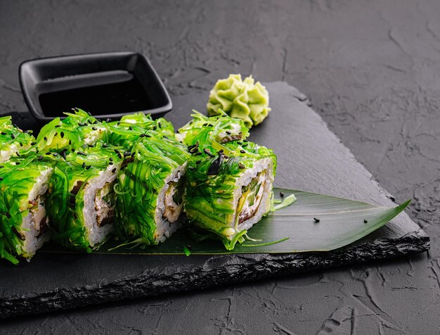 Un uramaki de sushi décoré de wasabi et d'une salade d'algues