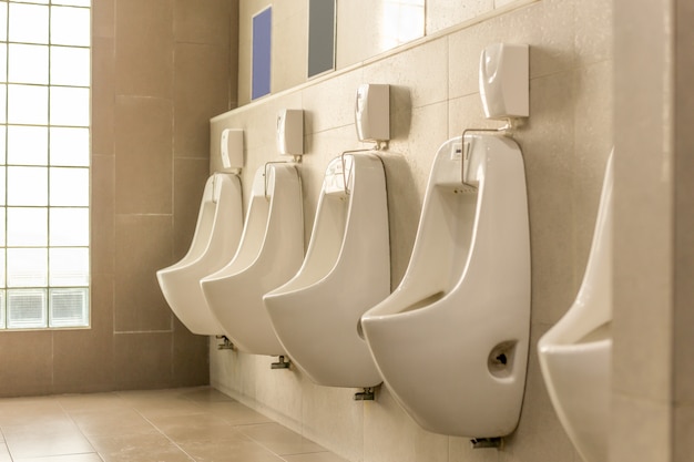 Urinoirs blancs alignés dans les toilettes publiques pour hommes.