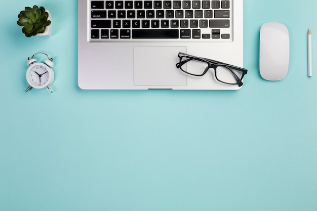 Usine De Cactus, Réveil, Ordinateur Portable, Lunettes, Souris Et Crayon Sur Le Bureau Bleu