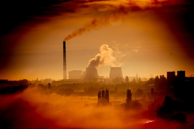 Usine avec cheminées et fumée dans l'orange