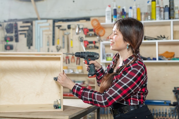 Usine de meubles, petites entreprises et concept de travailleuse - femme avec une perceuse